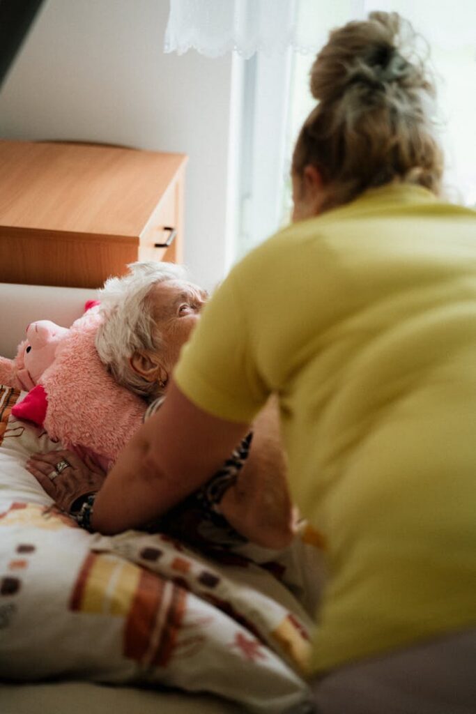 Nurse assisting elderly woman in a comfortable medical facility setting.