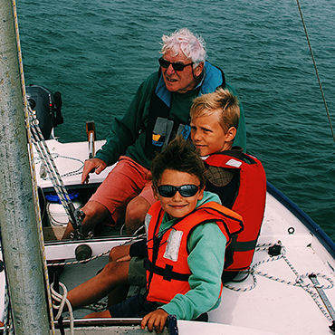 Kids on a boat with father, with life jackets on.